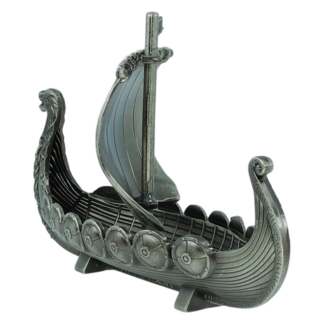 The Faire - Scandinavian Specialties Figurine: Norwegian Viking Ship with Sail Pewter 5″x3″ Table Decor features a silver-toned model of a Viking longship, complete with an intricately detailed dragon head prow, shield decorations lining the sides, and a single mast topped with a sail. Celebrating Scandinavian heritage, this pewter decor piece is showcased on a plain white background.