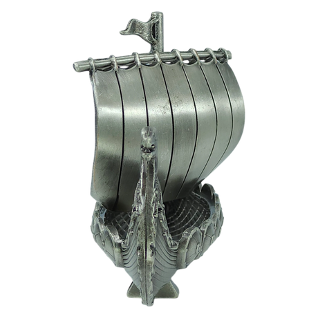 A handcrafted pewter Norwegian Viking ship figurine by Faire - Scandinavian Specialties, featuring a curved hull, decorated prow, and vertical slats forming the sail—this 5″x3″ table decor piece is a front-view keepsake reminiscent of a traditional longship.