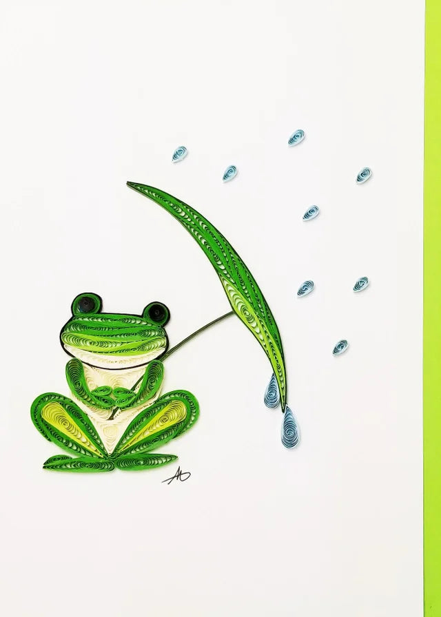 This handcrafted quilling card features a green frog with an umbrella, surrounded by blue raindrops, showcasing the artistry of high-quality paper.