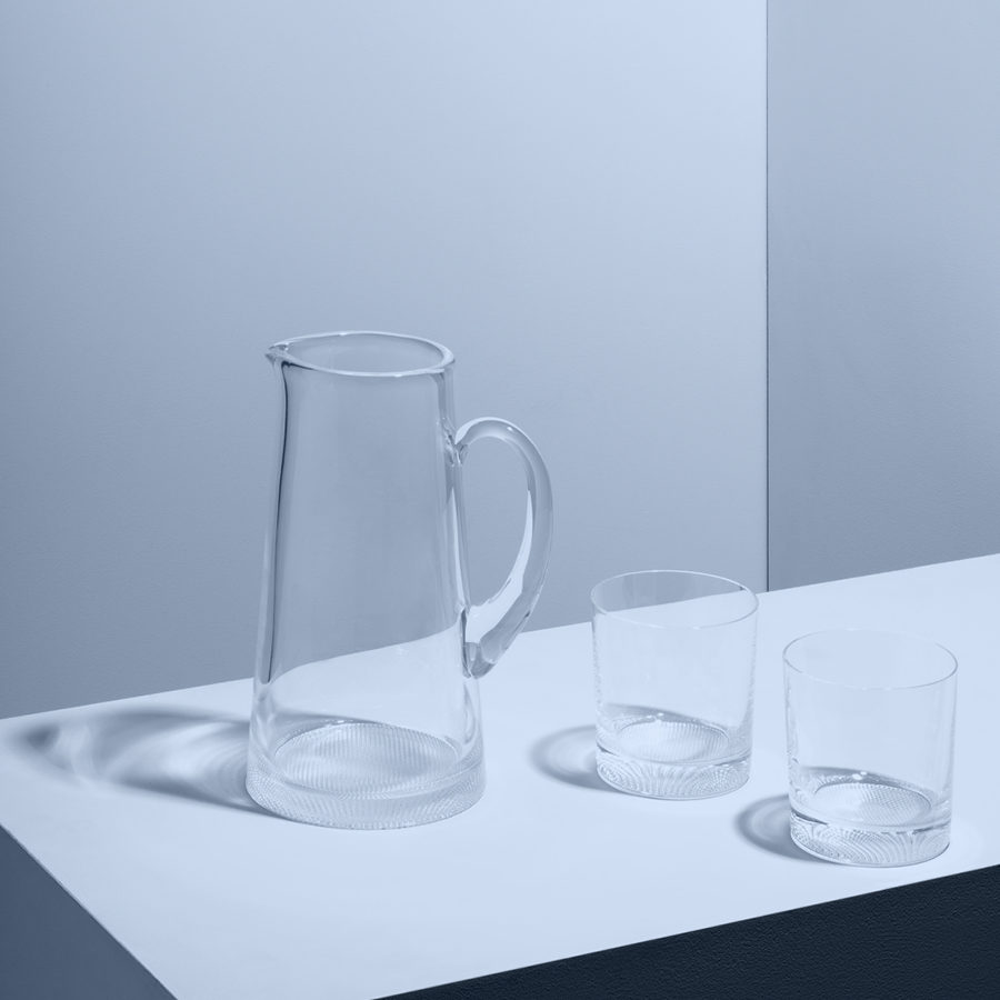 The KostaBoda Limelight Gift Set, featuring a clear glass pitcher and two double old-fashioned glasses, is elegantly displayed on a white surface against a minimalistic backdrop. Perfect for modern homes, this set is also dishwasher safe.