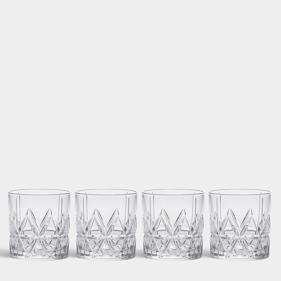 Four Orrefors Peak Double Old Fashioned 11.5 oz glasses, designed by Martti Rytkönen, are elegantly lined up. Their faceted design reflects light beautifully against the plain white background.