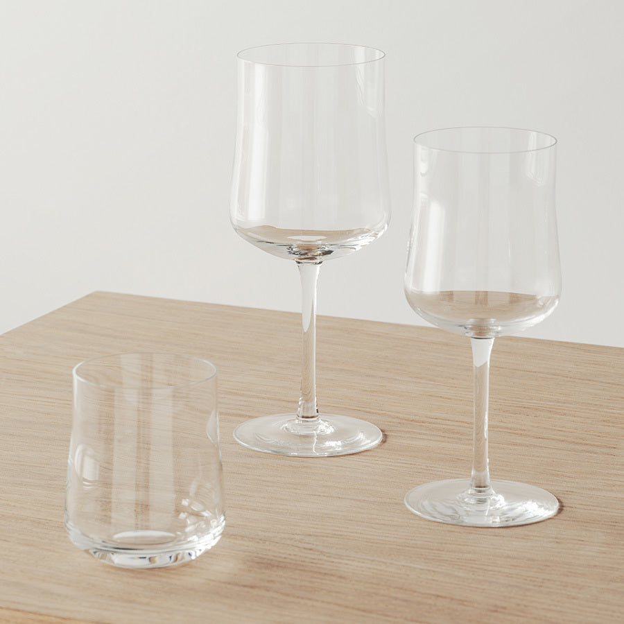 Two Orrefors Informal Glasses, each with a 9.5oz capacity, showcase Scandinavian design elegance. Resting on a light wooden surface against a plain backdrop, these empty glasses embody renowned craftsmanship and offer an understated blend of form and function.