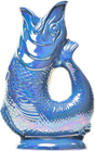 The Gluggle Jug: Gluggle Jug Lustre Made in Europe is a shiny blue, fish-shaped pitcher with textured scales, an open mouth, and a lustre glaze, designed to stand upright on a flat base.