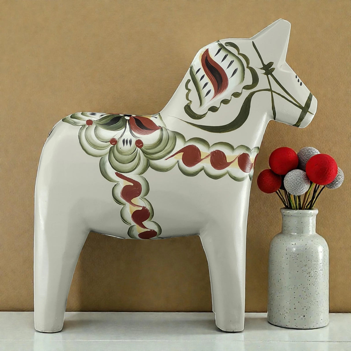 A handcrafted gray Swedish Dala Horse "Anders / Anniversary Series" by Grannas Olsson (13 cm) stands beside a speckled vase with red, gray, and white felt ball stems, all set against a beige background.