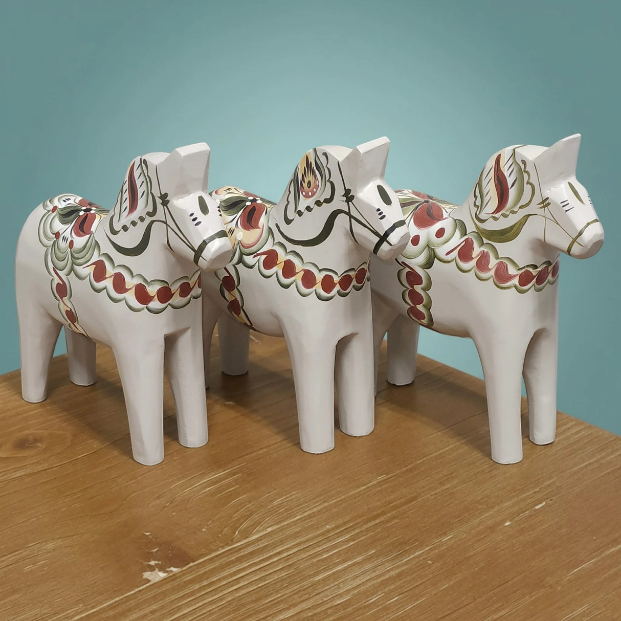 The “Anders / Anniversary Series” gray Swedish Dala Horse by Grannas Olsson is a 13 cm handcrafted wood figurine, painted in Sweden with red, green, and gold patterns—reflecting traditional Swedish craftsmanship.