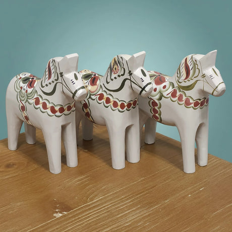 The “Anders / Anniversary Series” gray Swedish Dala Horse by Grannas Olsson is a 13 cm handcrafted wood figurine, painted in Sweden with red, green, and gold patterns—reflecting traditional Swedish craftsmanship.