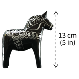 The Grannas Olsson "Celebrate Series" Black & Silver Swedish Dala Horse is a handcrafted 13 cm (5 in) figurine inspired by traditional folk art, featuring decorative patterns.