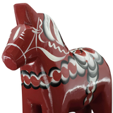 Close-up of the Grannas Olsson Dala Horse: Burgundy "Maria / Anniversary Series" (15 cm), handcrafted in Sweden with white, black, and gray patterns, set against a white background.