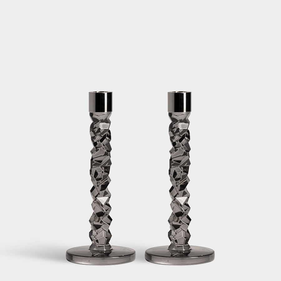 The Orrefors: Carat Candlestick Graphite 2-Pack features two geometric-patterned, graphite-hued candlestick holders with round bases on a plain background.