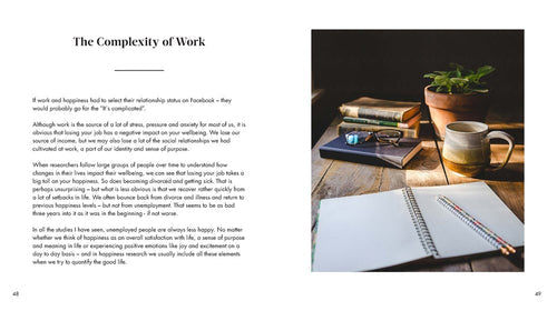 A notebook and pen on a wooden table with a coffee and small plant, alongside text from The Art of Danish Living: How the Worlds Happiest People Find Joy at Work by Meik Wiking, exploring work complexity through Danish lifes happiness emphasis.