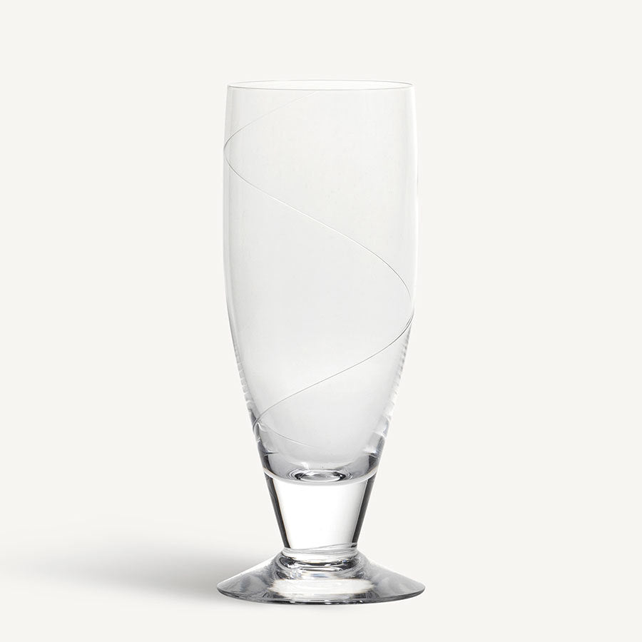 The KostaBoda: Line Iced Beverage Glass 17oz flaunts an exquisite, spiral design on mouth-blown glass, gracefully standing on a flat base. A superb example of Swedish craftsmanship, its ideal for serving your favorite iced beverage in style.