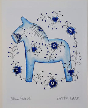 The artwork Blue Horse Blue Fluted by Greta Lann depicts a blue Dala Horse adorned with intricate blue and black floral patterns, surrounded by elegant floral swirls on a white background.