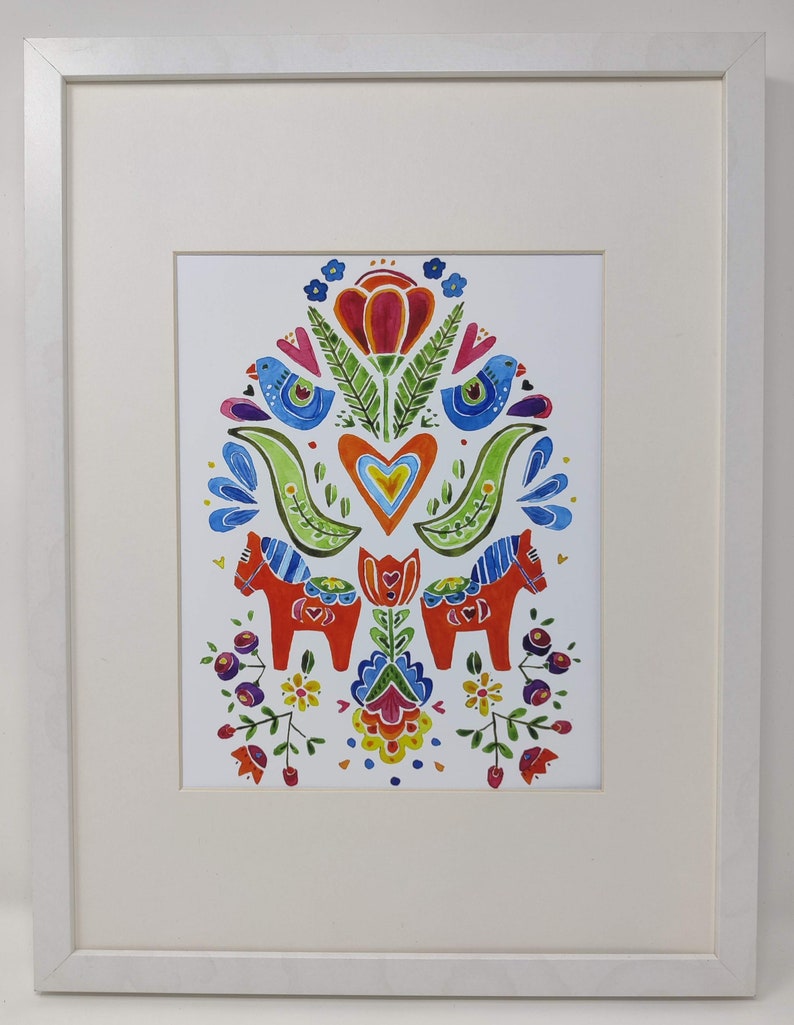 Framed original art titled "Spring Folk Horses" by BlueGreta Lann, showcasing two symmetrical birds in vibrant colors with intricate folk flowers and two red horses at the bottom.