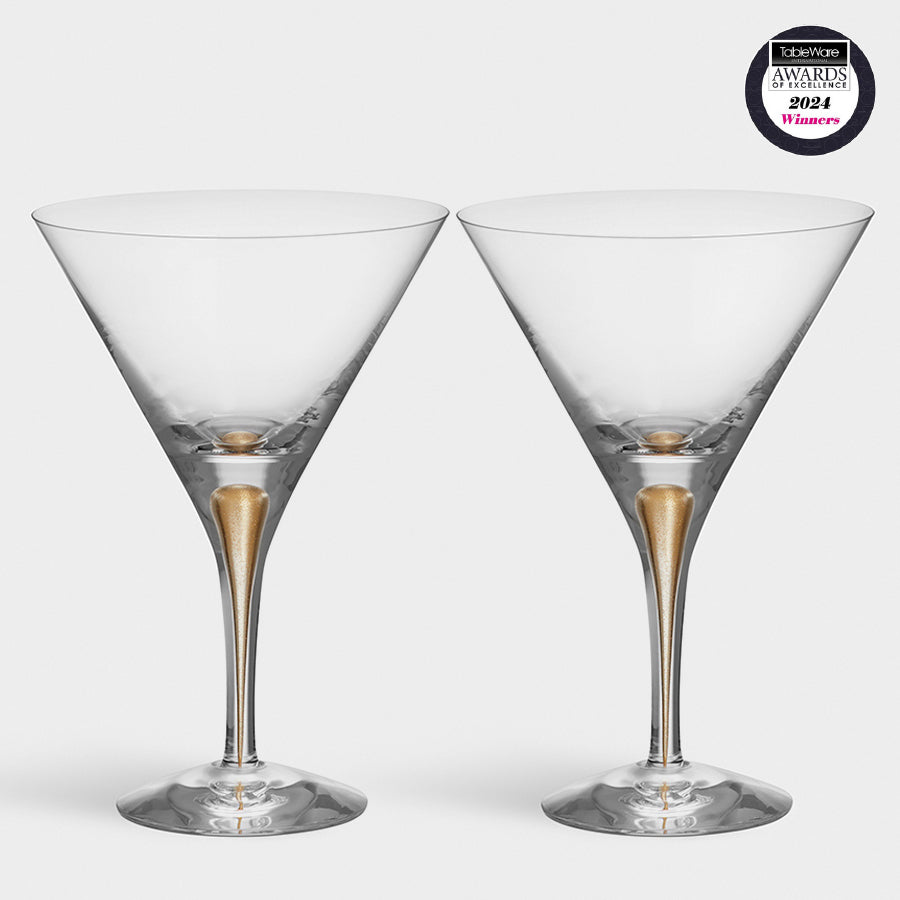 Two Orrefors: Intermezzo Gold Martini 8.5oz glasses with gold stems, crafted from mouth-blown glass, sit on a pristine white background featuring an award badge in the top right corner.