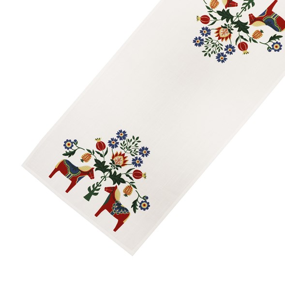The Dala Horse and Kurbits Table Runner (40x120cm) is a white Swedish table runner with colorful floral motifs and three red stylized Dala horses at one end, inspired by Scandinavian folk art.