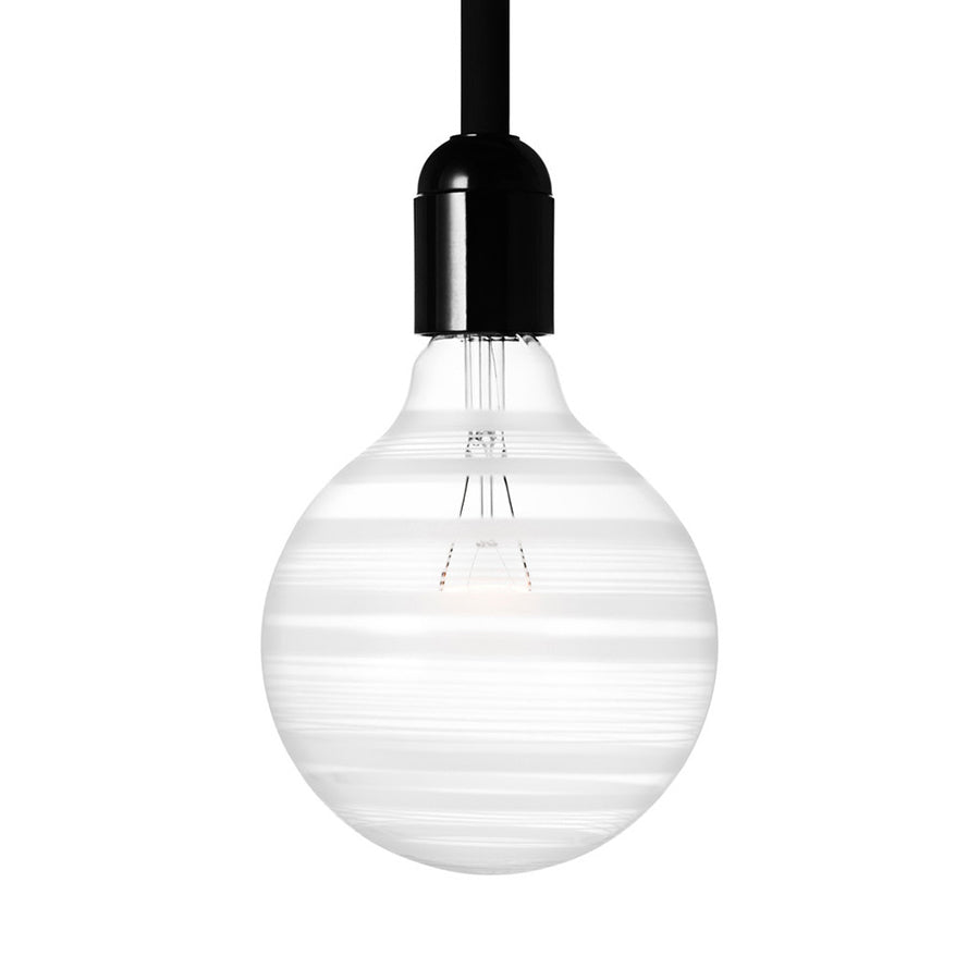 The Orrefors Light Shadows Bulb Line 25W, featuring horizontal stripes and suspended from a black cord, epitomizes minimalist design against a white background.