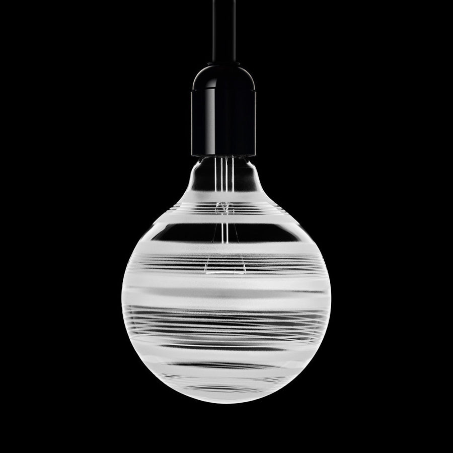 Orrefors Light Shadows Bulb Line 25W features a minimalist design with a spherical bulb and striped pattern, resembling a pendulum lamp against a black background.