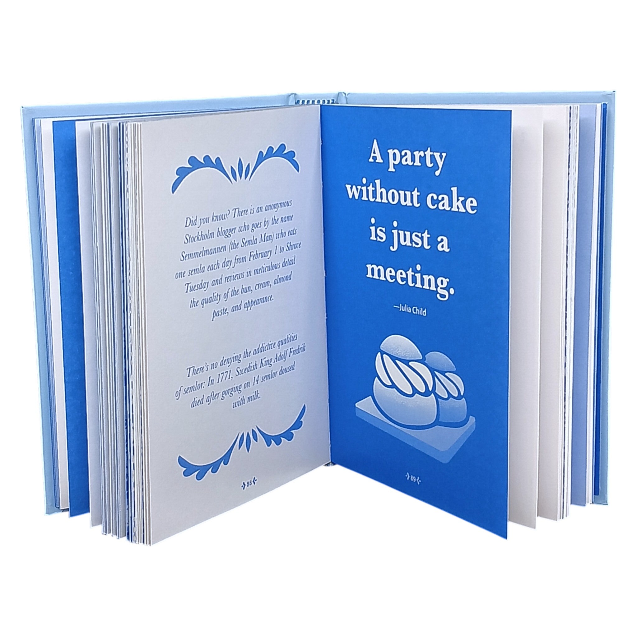 An open copy of "Little Book of Fika" by Lynda Balslev shows a blue page with Julia Child’s quote, “A party without cake is just a meeting,” and cake illustrations—inspiring the Swedish coffee break tradition. The other page has text and decorative borders.
