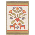 The Tea Towel: Kurbitsblom showcases an embroidered design with two orange dalahorses, flowers, and leaves made from organic cotton. It is highlighted by green, red, and tan borders.