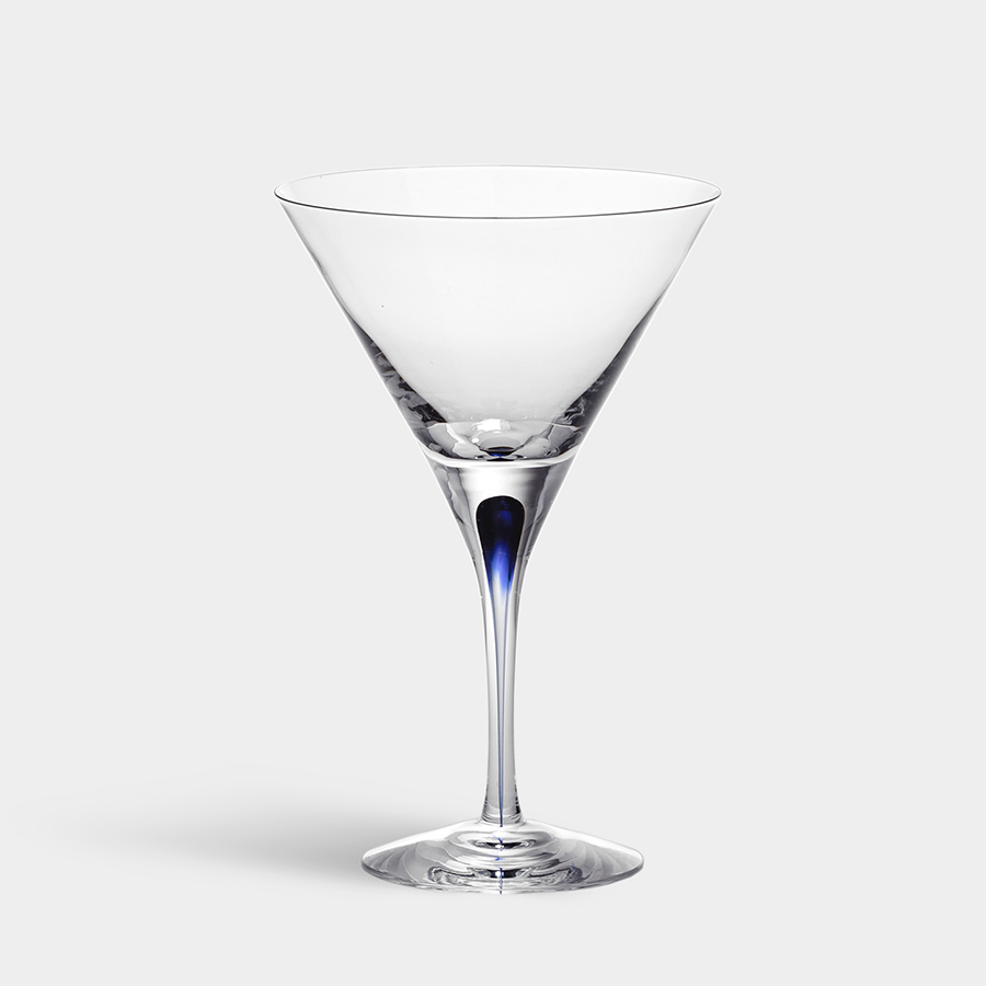 The Orrefors Intermezzo Blue Martini Glass, designed by Erika Lagerbielke, showcases a clear bowl with a unique blue accent on the stem, all set against a plain background.