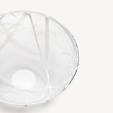A KostaBoda Contrast Bowl by Anna Ehrner, crafted from clear glass with white, blue, and black veining, displayed on a plain white background.