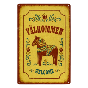 Rectangular metal sign featuring a Dala horse, floral rosemaling patterns, and the text VÄLKOMMEN and WELCOME.