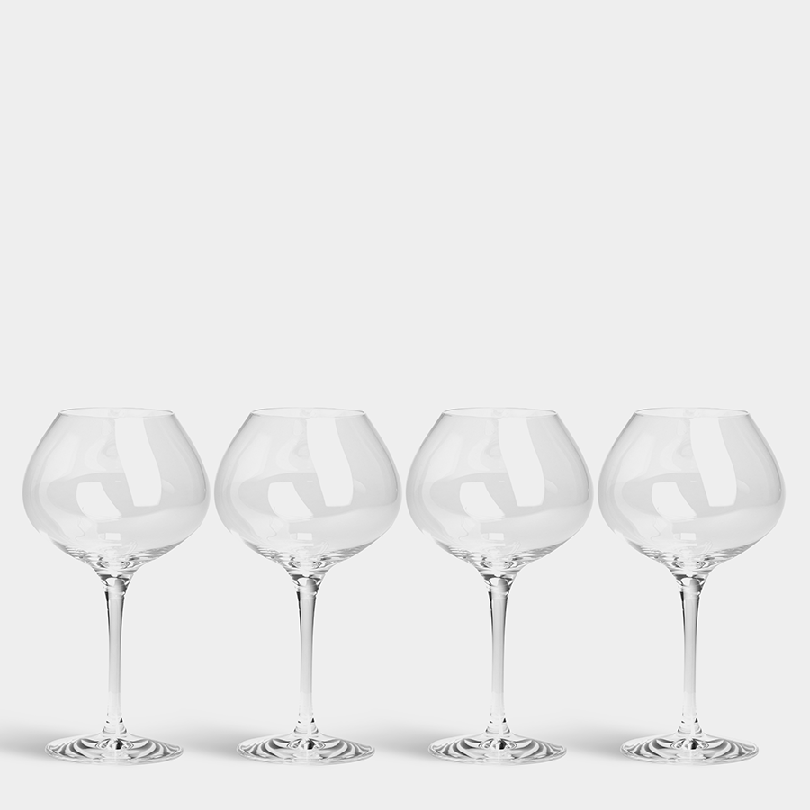 A set of four Orrefors: More Mature Glass 16oz, with elegant thin stems, is displayed in a line against a pristine white backdrop.