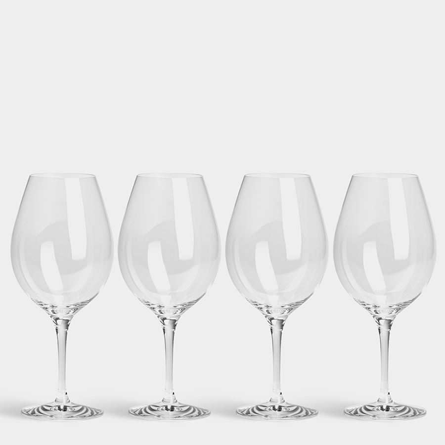 Four Orrefors More Wine XL 20oz glasses, part of a 4-pack, designed by Erika Lagerbielke, rest elegantly in a row on a crisp white background.