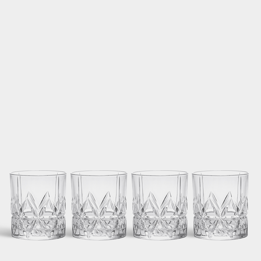 The Orrefors Peak Old Fashioned Glass set includes four clear cut tumblers with a geometric pattern, beautifully arranged in a row on a plain white background, reminiscent of classic craftsmanship and adding elegance to any setting.