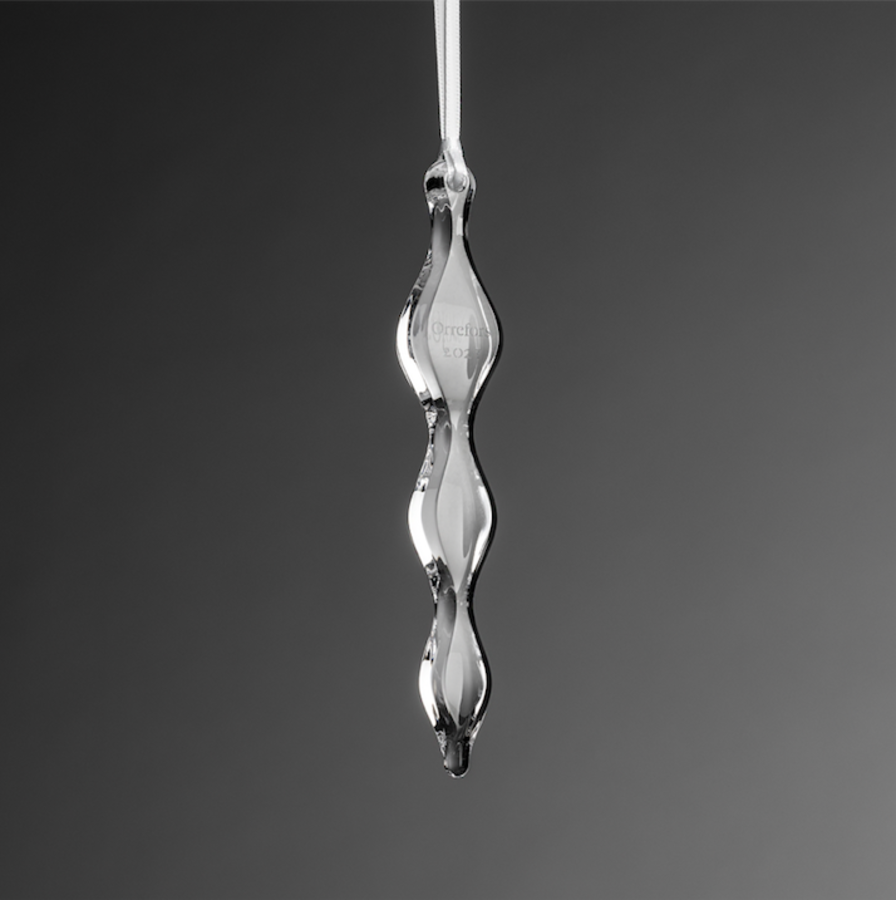 The Orrefors: Annual Ornament Icicle, a twisted, clear glass creation, hangs elegantly against a solid gray background.