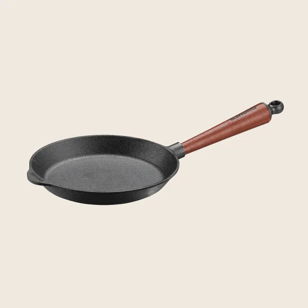 The Skeppshult Skillet With an 8.6 walnut handle offers excellent heat conduction for even cooking, featuring a long brown handle against a light background.