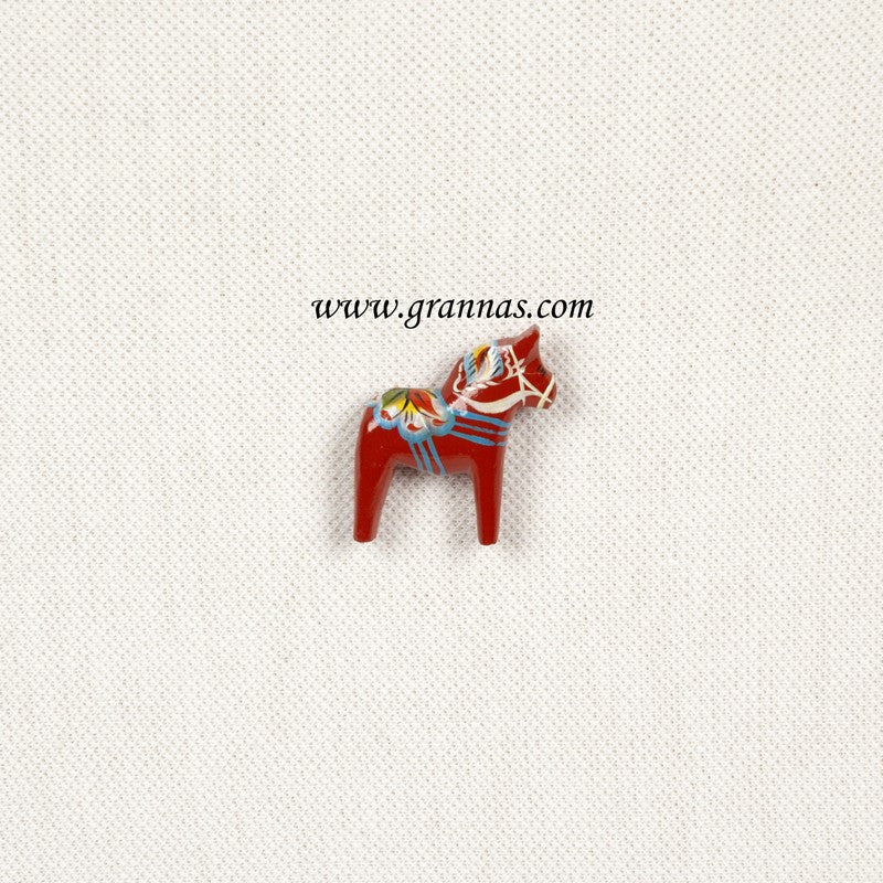 The 1.25 Red Swedish Dala Horse Pin, adorned with colorful kurbits decoration, rests on a light textured background.