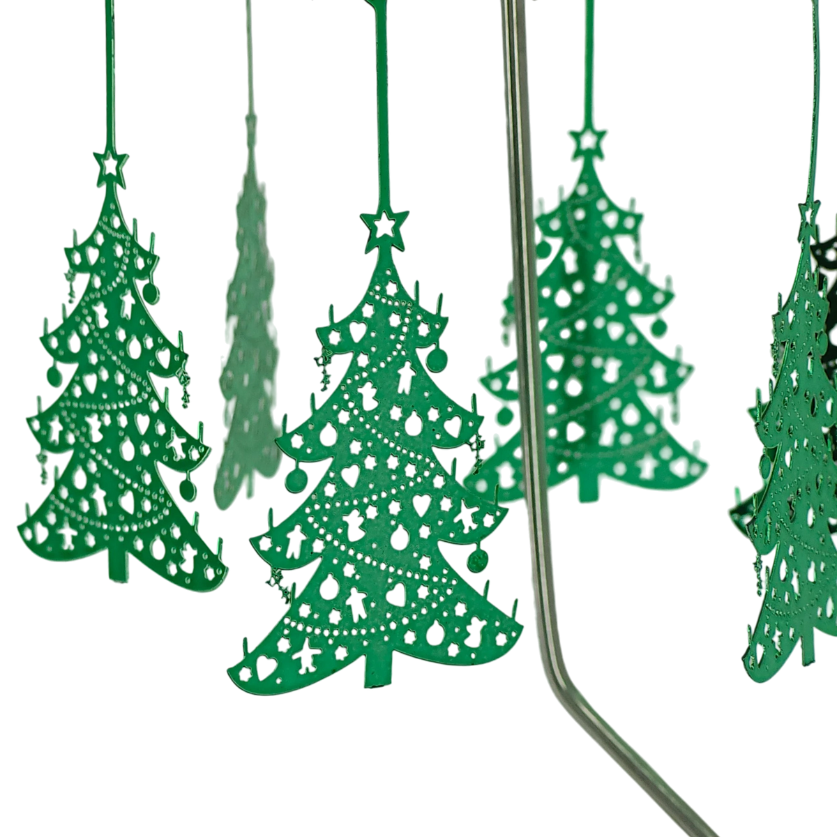 Green metal ornaments with cut-out designs hang from thin rods on a chrome Swedish rotary candle holder, with part of the stand visible on the right side.