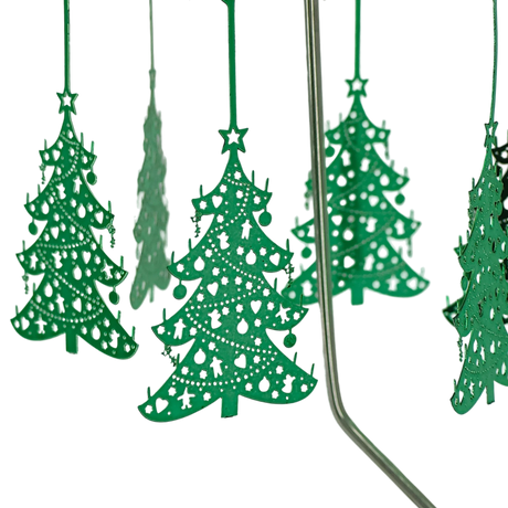 Green metal ornaments with cut-out designs hang from thin rods on a chrome Swedish rotary candle holder, with part of the stand visible on the right side.