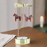 Gold-colored metal Swedish rotary candle holder with hanging red Dala horse ornaments featuring traditional painted patterns.