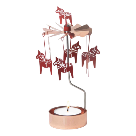 Rose gold Dala Horse metal figures spin on a rotary candle holder above a tealight in a copper holder, shown against a plain white background.