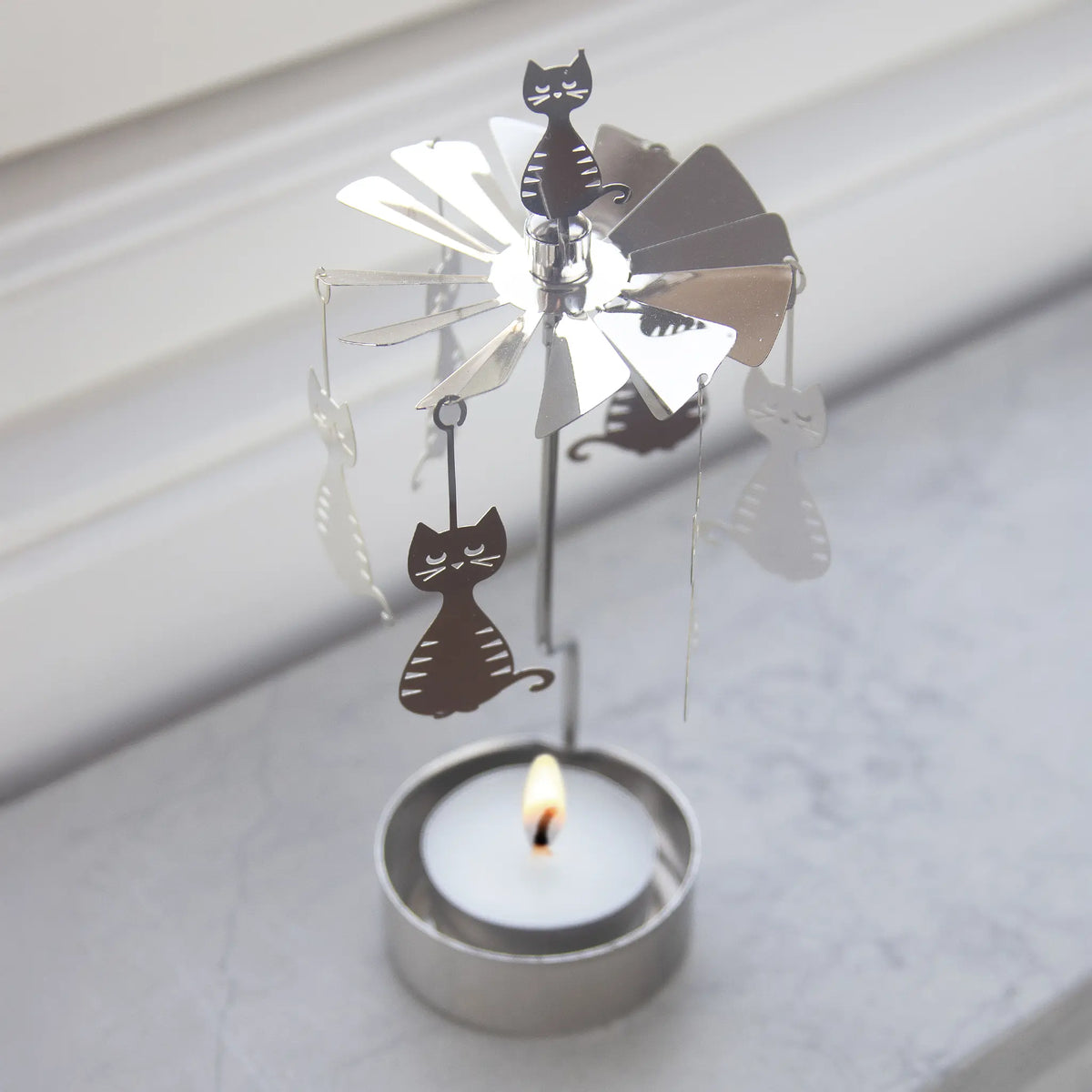 Silver rotary candle holder with hanging cat silhouettes and a tealight.