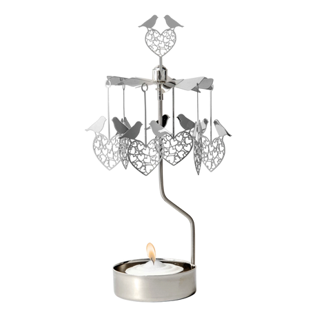 Rotary candle holder with love bird and heart shapes suspended above a lit tealight, all crafted from silver-toned recycled metal.