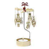 Gold-colored Swedish rotary candle holder featuring hanging nutcracker and ornament silhouettes, topped with a red bow.