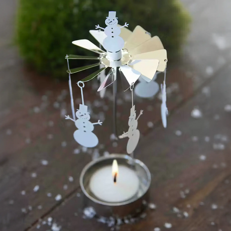 A metal rotary candle holder with hanging snowman ornaments above a lit tealight.