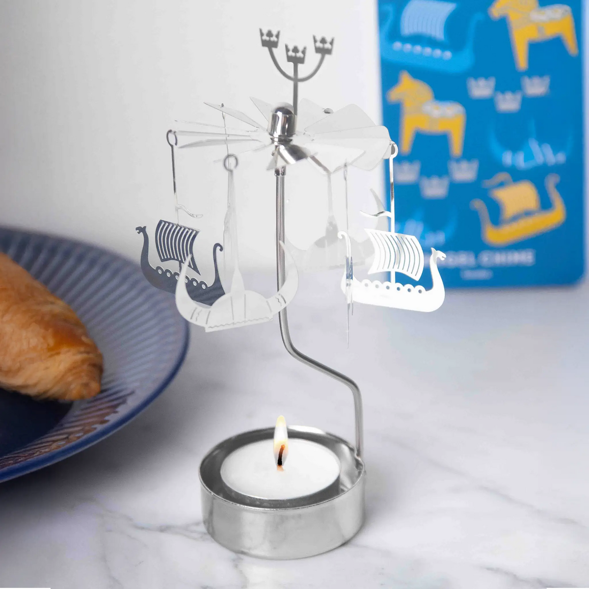 Metal rotary candle holder with hanging Viking ship ornaments.
