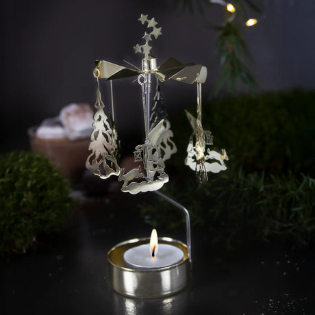 Gold-toned metal rotary candle holder with hanging tree and rabbit ornaments and a lit tealight at the base.