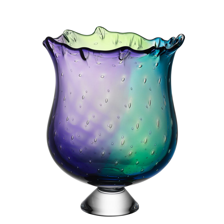 The Kosta Boda Poppy Bowl, designed by Kjell Engman, showcases a multicolored glass creation with a wavy rim and textured surface, artfully blending shades of purple, blue, and green on a clear round base.