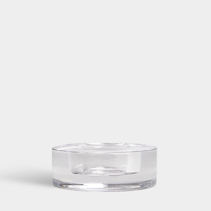 A clear, cylindrical Orrefors: Puck Votive Candle Holder with a flat base is set against a plain white background, ideal for use as a candle holder or decorative piece.