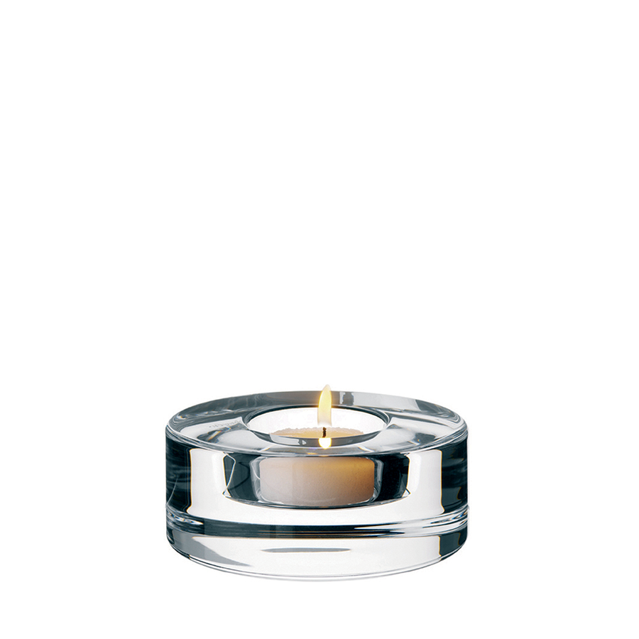 The Orrefors: Puck Votive Candle Holder elegantly cradles a tealight in its clear round glass, beautifully showcased against a white background.