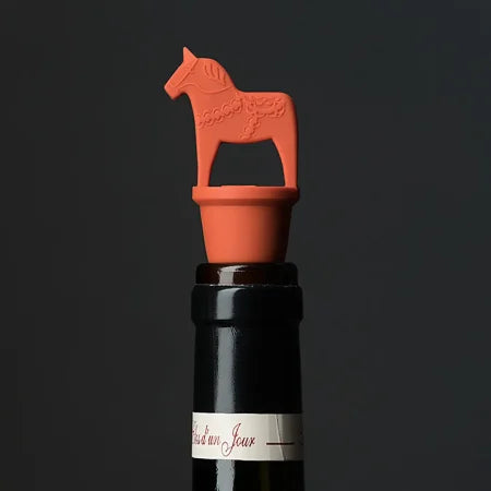 A wine bottle is sealed with the Red "Vinkork" Wine Cork Bottle Stopper, featuring a charming design, set against a plain dark background.