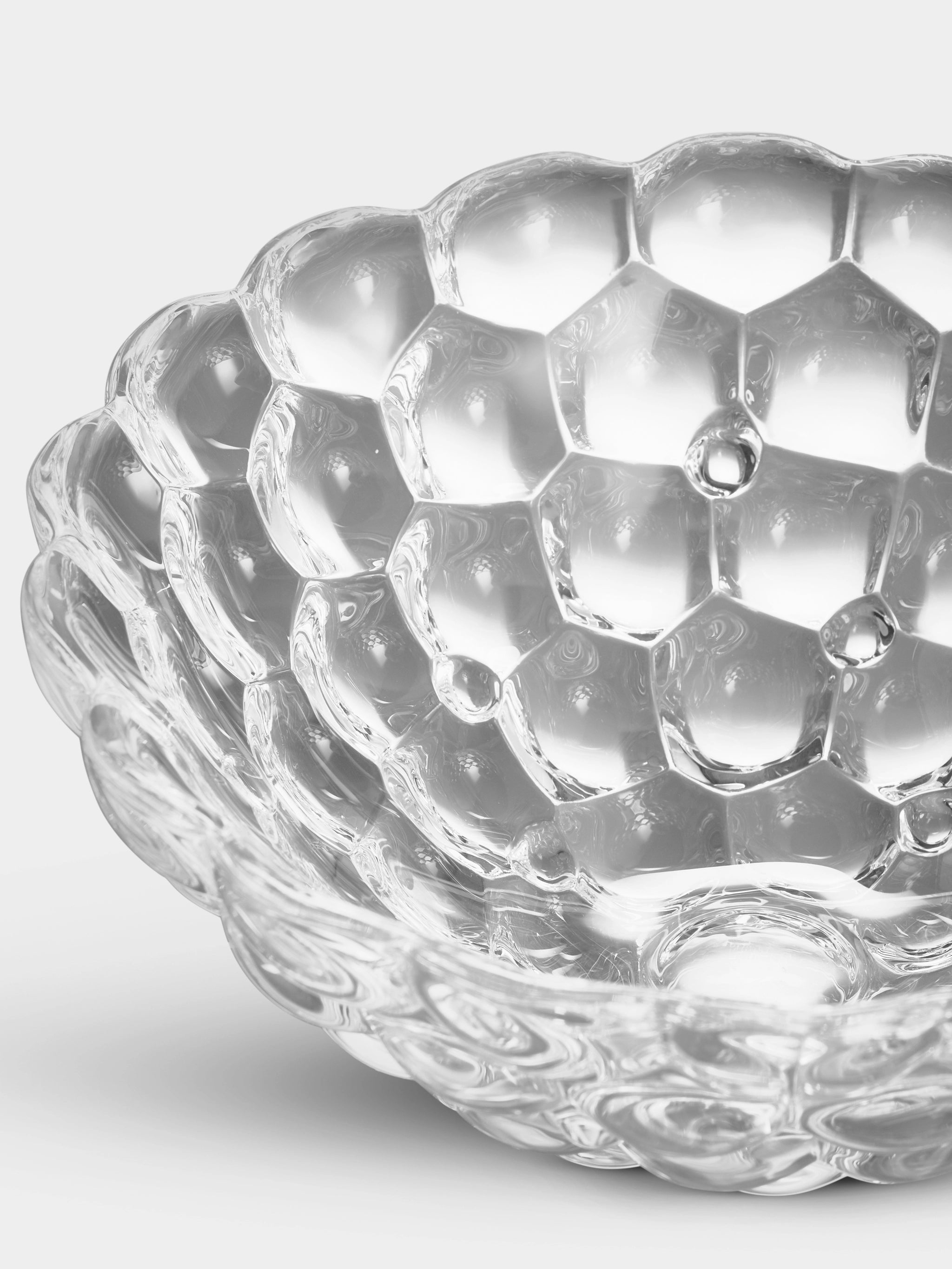 Close-up of the Orrefors: Raspberry Bowl Small, made of crystal glass with a captivating honeycomb design, set against a light background.