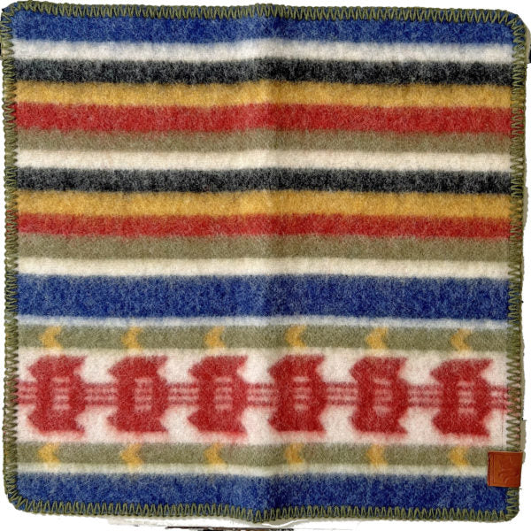 The Seat Pad: RATTVIK, designed by Kerstin Landstrom, is made from 100% Norwegian organic lambswool and showcases multicolored horizontal stripes in red, blue, yellow, gray, and black. With its decorative edge and geometric motifs reminiscent of the Rättvik pattern, it offers both warmth and a striking visual appeal.