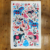 The Lotta Spjute Home Decor Bundle features a tea towel and trays with vibrant Scandinavian horse and floral patterns in blue, pink, red, and black—perfect Swedish art-inspired kitchen accessories—displayed on a wooden surface.