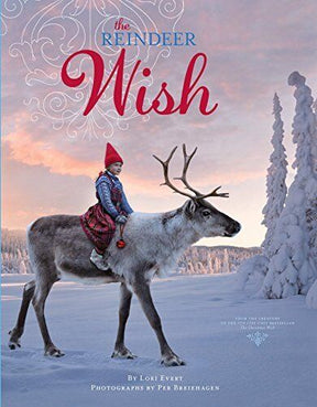 In a snowy landscape, a child dressed in winter attire gently sits atop a standing reindeer, with "Reindeer Wish" captivating young readers at the top of the image.